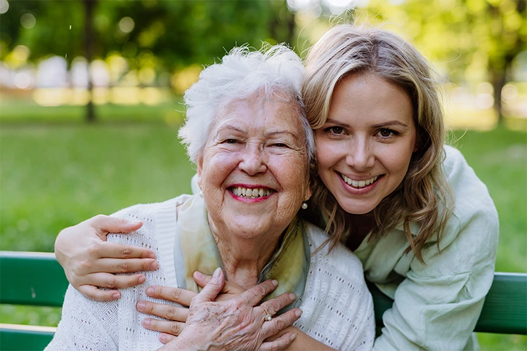 Senior woman and her adult child caregiver smiling
